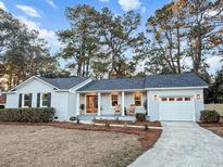 Charming one-story home with gray painted brick and inviting front porch with rocking chairs at 1109 Calm Water Ct, Mount Pleasant, SC 29464