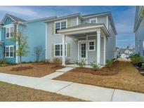 Charming two-story home with light gray siding, covered porch, and manicured lawn at 143 Brant Dr, Summerville, SC 29483