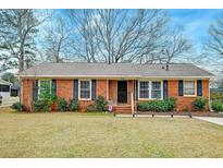Charming brick home featuring a well-maintained lawn, trimmed bushes, and classic black shutters at 3351 Londonderry Rd, North Charleston, SC 29420