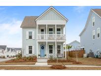 Charming two-story home with double porches, a blue front door, and meticulously landscaped yard at 46 Clearblue Loop, Summerville, SC 29486