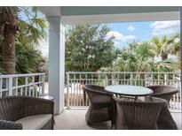 Relaxing balcony with wicker seating, outdoor table, and picturesque views of palm trees at 5800 Palmetto Dr # R-Vg102, Isle of Palms, SC 29451