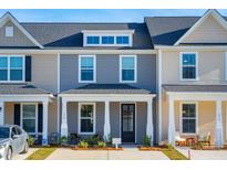 Charming townhome with modern gray and tan siding, black door, covered porch, and manicured landscaping at 822 Alma Square Dr, Moncks Corner, SC 29461