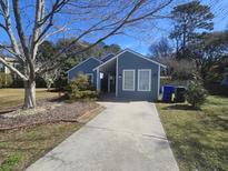 Charming blue house featuring a driveway, complemented by landscaped yard and a tree at 1060 Oakcrest Drive, Charleston, SC 29412
