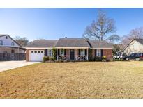 Charming brick home with a covered front porch, white picket fence, and well-manicured landscaping at 1649 Lauda Dr, Mount Pleasant, SC 29464