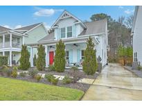 Charming two-story home featuring a landscaped front yard, bright red door, and light blue window shutters at 1702 Sparkleberry Ln, Johns Island, SC 29455