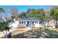 Charming single-story home featuring a bright blue door and solar panels in a well-maintained lawn at 2440 Lantern St, Charleston, SC 29414