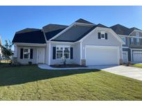 Well-manicured lawn highlights this beautiful single Gathering home with a two-car garage, a cozy white door, and black window shutters at 478 Rowley Ln, Summerville, SC 29486