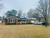 Charming brick home featuring solar panels, attached garage and a well-maintained front lawn at 2005 Saint David Ln, Charleston, SC 29414