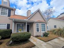 Charming two-story townhome with tan siding, mature landscaping, and a cozy front porch, ideal for relaxing outdoors at 409 Reserve Way, Summerville, SC 29485