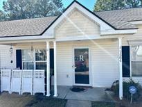 Welcoming front entrance of home featuring a covered porch, white columns, and ADT security sign at 7364 Suncatcher Dr, Hanahan, SC 29410