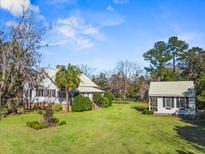 Charming home with large front yard, lush landscaping, and a guest house with a matching green metal roof at 901 Morton Waring Ln, Pinopolis, SC 29469