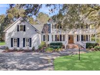 Charming two-story white home with black shutters, inviting front porch, and beautiful landscaping at 100 Oak Village Ln, Summerville, SC 29483