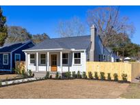 Charming home featuring stylish landscaping, a wooden fence, a stone chimney, and a cozy front porch at 1126 Arant St, North Charleston, SC 29405