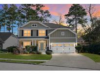 Charming two-story home with manicured lawn, mature trees, and a two-car garage at sunset at 188 Donning Dr, Summerville, SC 29483