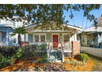 Charming home with mature landscaping, front porch, brick accents, and bright red front door at 12 Poplar St, Charleston, SC 29403