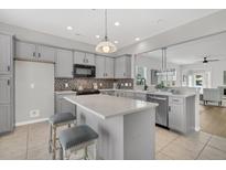 Bright kitchen features gray cabinets, stainless steel appliances, mosaic backsplash and a center island with seating at 174 Sea Lavender Ln, Summerville, SC 29486