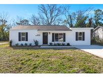 Charming single-story home featuring a well-maintained lawn, black shutters, and modern exterior lighting at 3113 Matipan Ave, North Charleston, SC 29405