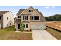 Charming two-story home with a two-car garage, black shutters, and a well-maintained front lawn at 585 Red Monarch Way, Moncks Corner, SC 29461