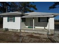 Cozy single-story home featuring white siding, a covered front porch, and a metal roof, surrounded by a chainlink fence at 1202 Forty-One Rd, Saint Stephen, SC 29479