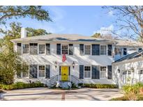 Charming two-story brick home with a bright yellow front door, manicured landscaping, and circular driveway at 14 Guerard Rd, Charleston, SC 29407