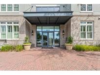Elegant building entrance with brick facade, covered walkway, and well-maintained landscaping with two planters at 200 River Landing Dr # 401A, Charleston, SC 29492