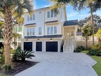 Charming two-story white home featuring a three-car garage and well-manicured landscaping at 27 22Nd Ave, Isle of Palms, SC 29451