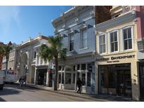 A view of the charming Charleston street featuring beautiful historic buildings and palm trees under a clear blue sky at 377 King St # 203, Charleston, SC 29401