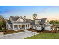 Beautifully landscaped home featuring a covered porch, multiple garage spaces and grey siding at 4 Preserve Rd, Johns Island, SC 29455