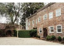 Charming brick home with a lush green landscape and gravel driveway at 42 1/2 Hasell St, Charleston, SC 29401