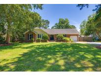 Charming brick home featuring a manicured lawn, lush landscaping, and attached garage at 740 Gypsy Ln, Mount Pleasant, SC 29464