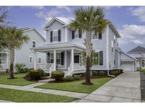 Charming two-story home with light blue siding, black shutters, front porch, and tropical landscaping at 1488 Croaton Xing, Mount Pleasant, SC 29466