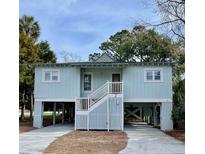 Charming stilt home with light blue siding, white trim, and well-maintained landscaping at 2 Sandcrab Ct, Isle of Palms, SC 29451
