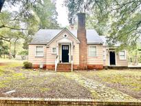 Charming single-story home featuring a brick chimney, inviting front porch, and landscaped surroundings at 411 Maplewood Dr, Walterboro, SC 29488