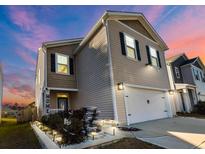 Charming two-story home featuring a water feature and an attached garage with a concrete driveway at 4916 Paddy Fld Way, Ladson, SC 29485