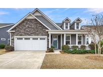 Charming home showcasing a stone facade, bright white garage door, and a cozy, covered front porch at 5049 Song Sparrow Way, Summerville, SC 29483