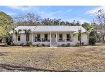 Charming single-story home with a metal roof and inviting front porch, surrounded by palm trees at 6294 Highway 165, Ravenel, SC 29470
