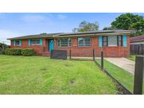 Charming brick home featuring a well-maintained lawn, vibrant blue door, and matching shutters at 1418 Kentwood Circle Cir, Charleston, SC 29412