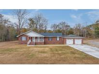 Charming brick home featuring a two-car garage, well-manicured lawn and inviting front porch at 242 Jacob Piland Rd, Moncks Corner, SC 29461