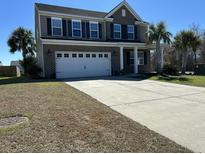 Two-story home featuring a brick facade, attached two-car garage, and a driveway surrounded by trees at 3072 Adventure Way, Ladson, SC 29456
