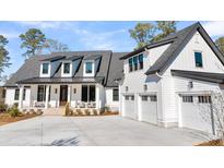 Beautiful two-story home boasts a three-car garage and charming front porch with ample parking on a concrete driveway at 3949 Bulow Landing Rd, Ravenel, SC 29470