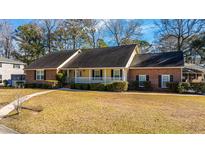 Charming ranch-style home with a brick facade, inviting front porch, and well-manicured lawn at 476 E Wimbledon Dr, Charleston, SC 29412