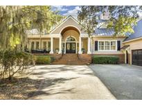 Elegant home with a welcoming front porch, manicured landscaping and spacious driveway at 65 Surfsong Rd, Kiawah Island, SC 29455