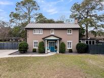Charming brick two-story home with a metal roof, manicured front yard, and blue front door at 739 Shamrock Ln, Charleston, SC 29412