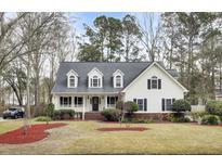 Charming two-story home with a cozy front porch and a well-manicured lawn and landscaped yard at 8656 Laurel Grove Ln, North Charleston, SC 29420