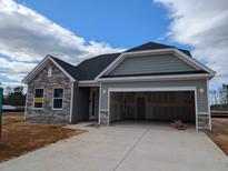 Charming single-story home featuring stone accents and an attached two-car garage with open doors and a large concrete driveway at 119 Palfrey Dr, Ridgeville, SC 29472