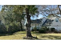 Charming home with a well-manicured lawn, mature trees, and a tranquil waterfront view at 1908 Oak Tree Ln, Mount Pleasant, SC 29464