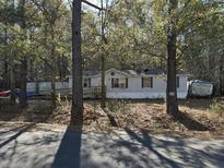 A single-story home features a wooden wheelchair ramp, light gray siding, dark shutters, and mature trees at 195 E Turner St, Summerville, SC 29483