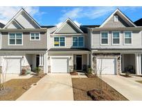 Charming townhomes featuring varied siding, attached garages, and manicured lawns under a sunny sky at 447 Duskywing Dr, Goose Creek, SC 29445