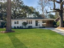 Charming brick home featuring a well-manicured lawn and mature shade trees on a sunny day at 5107 Temple St, North Charleston, SC 29405