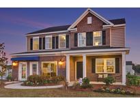 Two-story home featuring a brick facade, black shutters, covered porch, and manicured landscaping at 595 Red Monarch Way, Moncks Corner, SC 29461